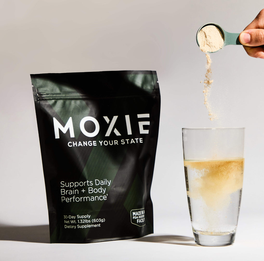 Photo of Moxie packaging next to a hand pouring a scoop of supplement into a glass of water