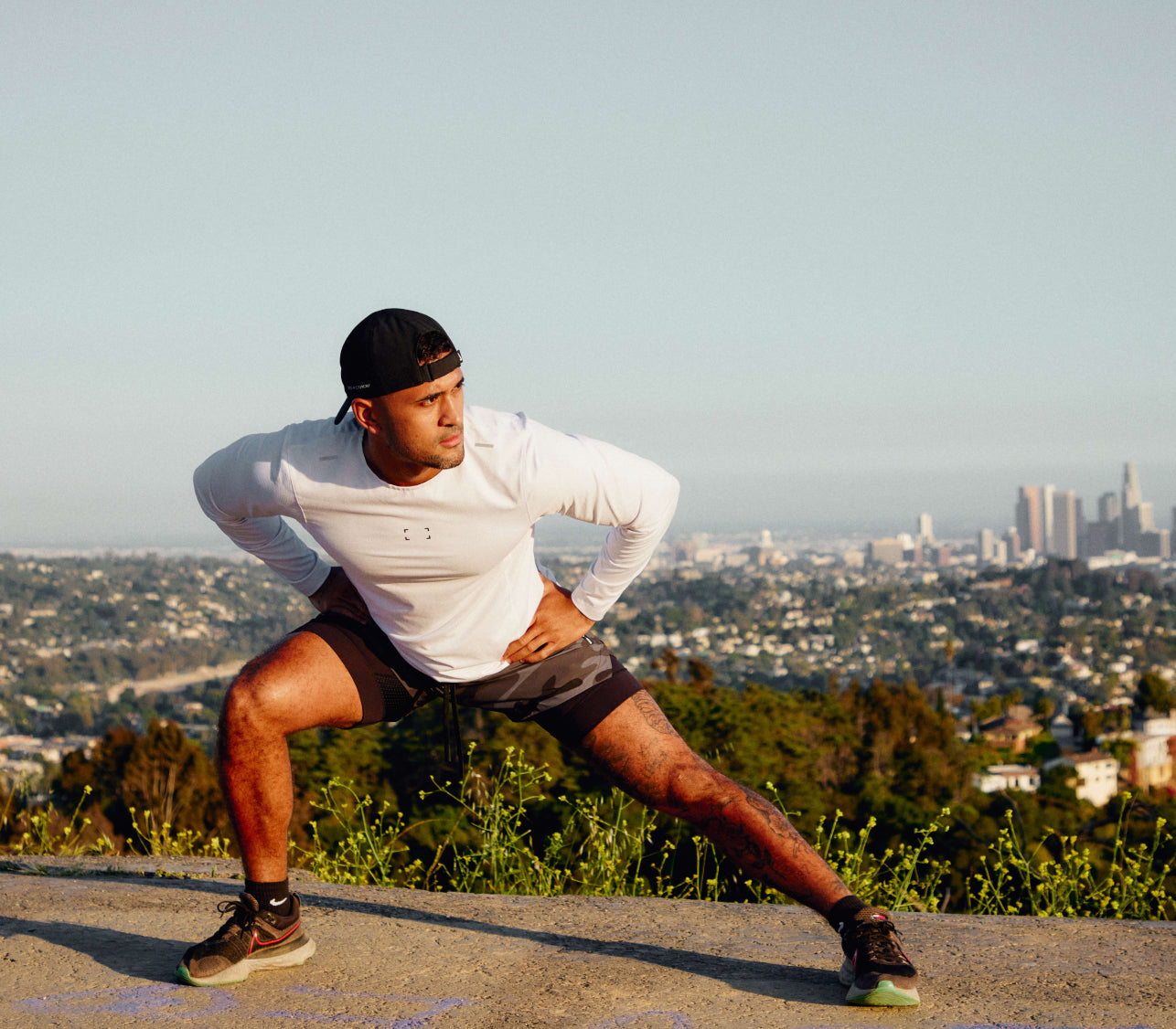 Photo of man stretching outdoors against the downtown Los Angeles skyline