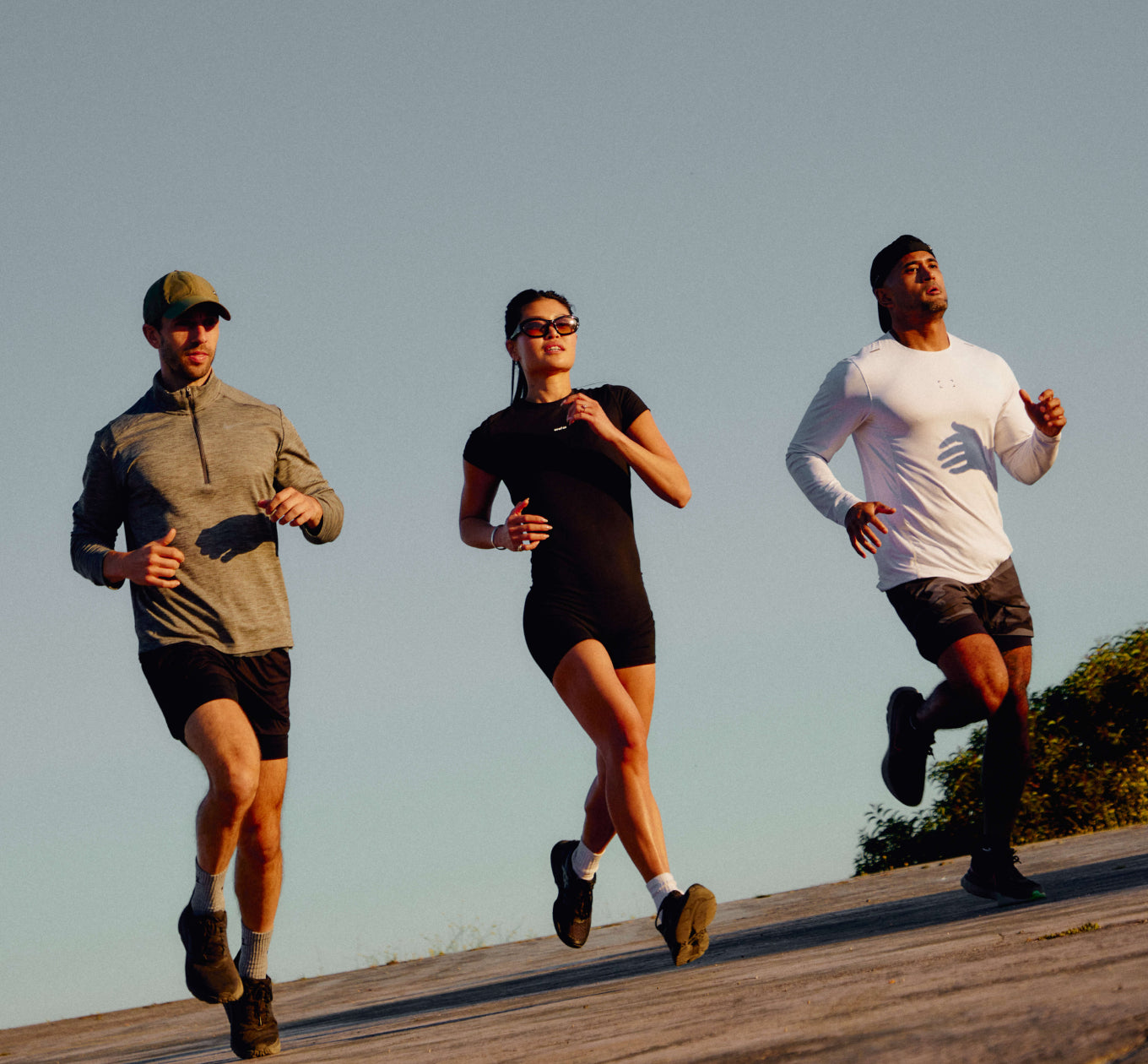 Photo of three athletic people jogging outside with warm lighting from sunset